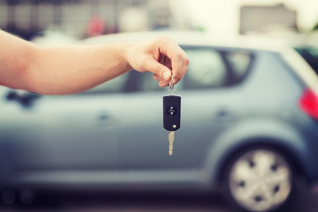 transportation and ownership concept - man with car key outside