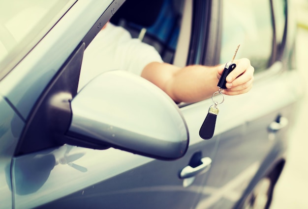 transportation and ownership concept - man with car key outside