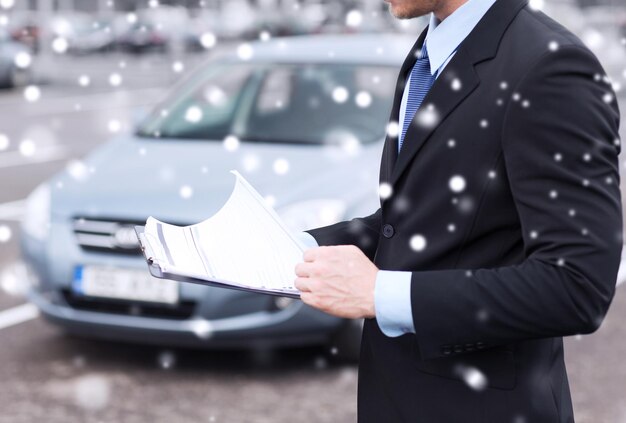 transportation, people, sale and ownership concept - close up of man with clipboard and car documents