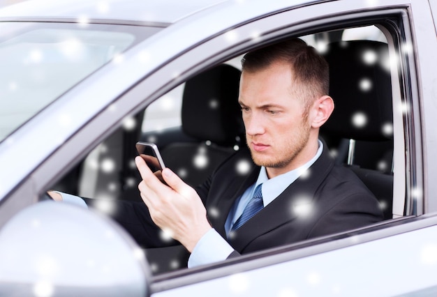 Trasporto, persone, tecnologia e concetto di veicolo - primo piano dell'uomo che utilizza lo smartphone durante la guida dell'auto