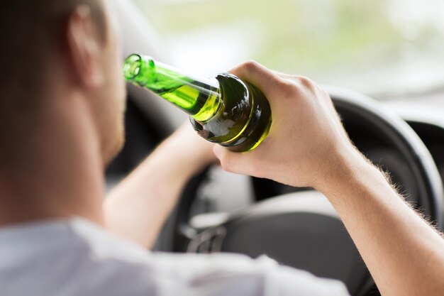 transportation and vehicle concept - man drinking alcohol while driving the car