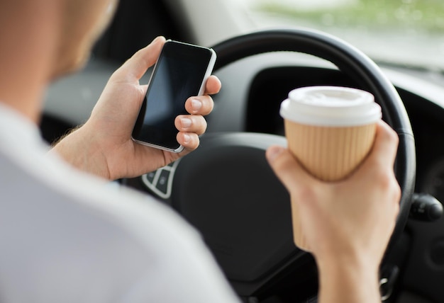 交通機関と車両のコンセプト-車を運転しながらコーヒーを飲み、電話を使用する男性