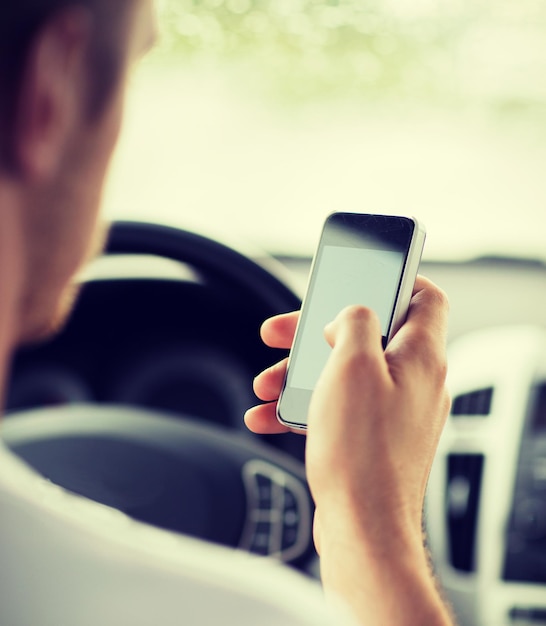 transportation and vehicle concept - man using phone while driving the car