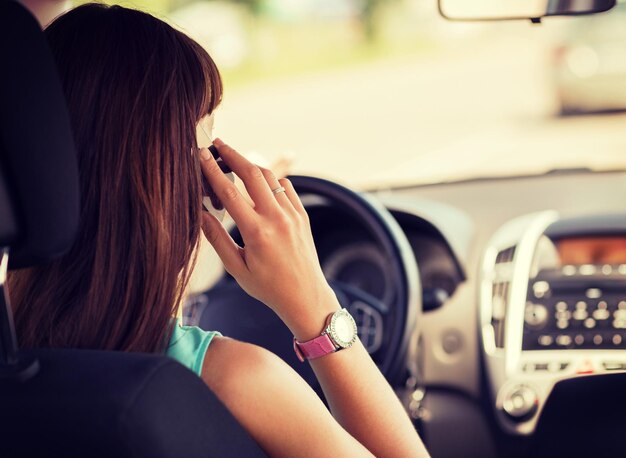 transportation and vehicle concept - woman using phone while driving the car