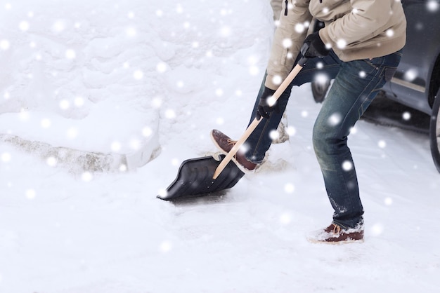 transportation, winter, people and vehicle concept - closeup of man digging snow with shovel near car