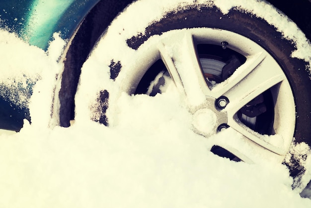 transportation, winter and vehicle concept - closeup of car wheel stuck in snow