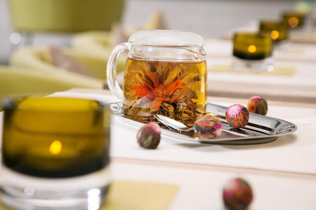 Transtarent tea pot with fresh green tea standing on an iron tray