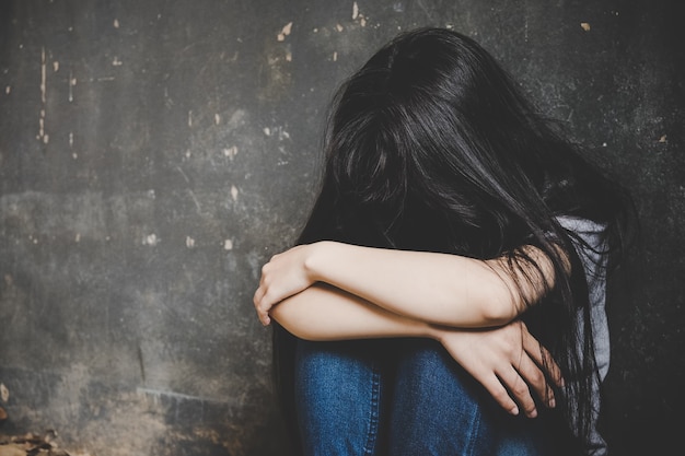 Trapped woman. young woman trapped sitting on the floor in a
dark room