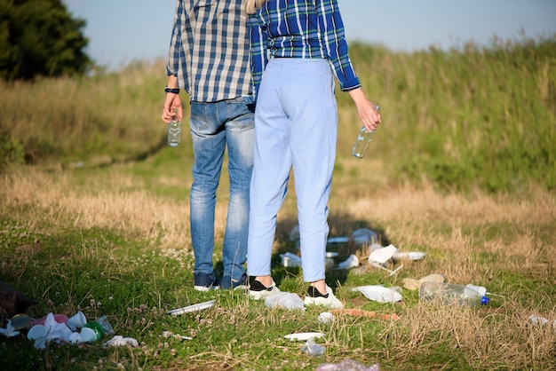 ビーチのゴミ箱。ゴミの山の隣のビーチで休んでいる若いカップル。人間と自然の概念