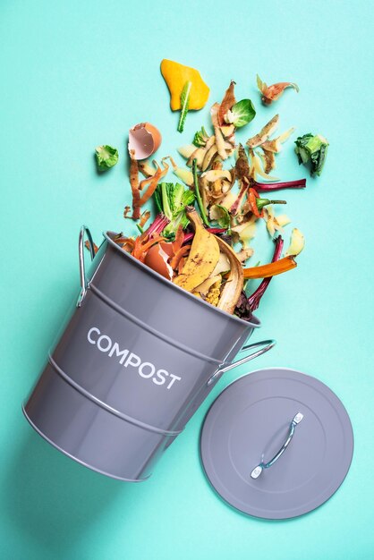 Trash bin for composting with leftover from kitchen on blue background Top view Recycling scarps concept Sustainable and zero waste lifestyle