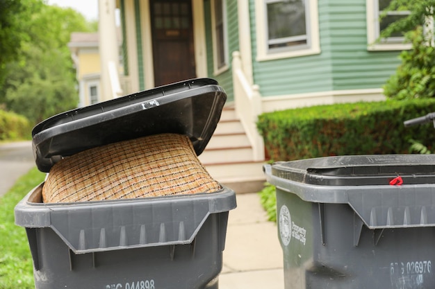 A trash can with a black trash bag in front of a house.