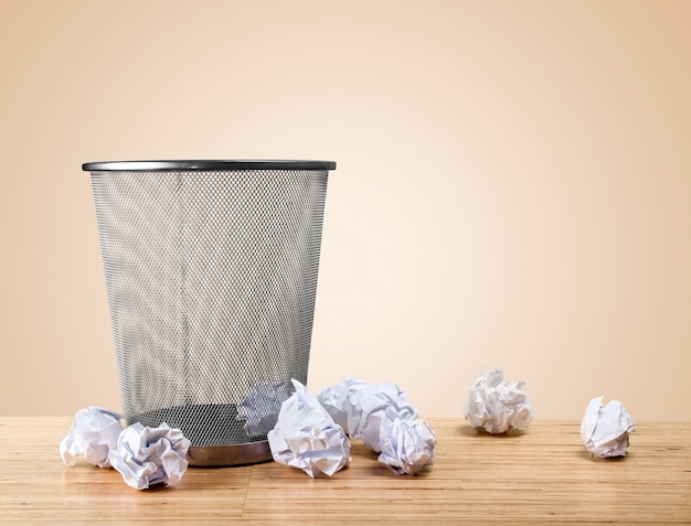 Trash can with paper sheets on wooden table