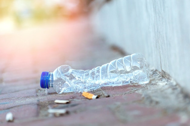 Trash on the ground of a city with cigarette butts and used plastic bottle. Eco concept.