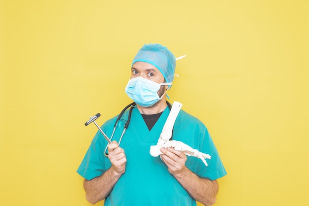 Trauma surgeon wearing an operating theatre uniform and stethoscope, checking a skeleton model of a foot, right lower limb, all on a yellow background.