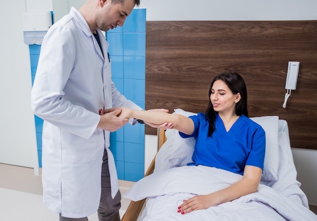 Traumatologist examining patient hands in modern hospital