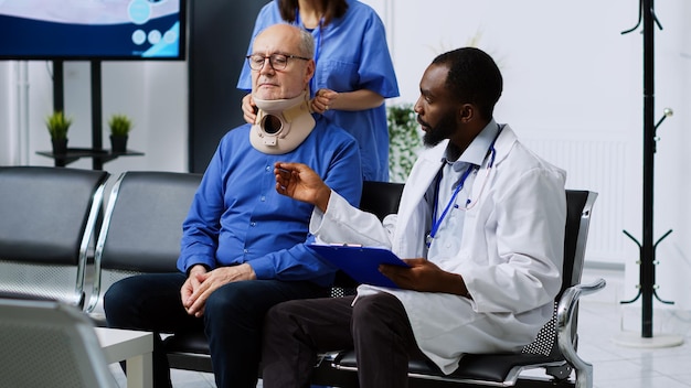 Травматологическая команда снимает шейный ошейник у азиатской пациентки с переломом шеи, страдающей от физической боли после аварии. Врач и медсестра поддерживают раненого в больничной приемной