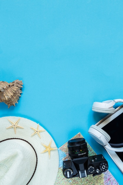 Фото Туристические аксессуары камеры, соломенная шляпа, карты, обувь на синем фоне, плоский вид сверху, макет с копией пространства