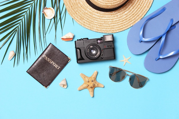 Travel accessories and tropical leaves on a colored background top view