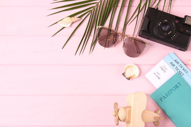 Travel accessories and tropical leaves on a colored background top view