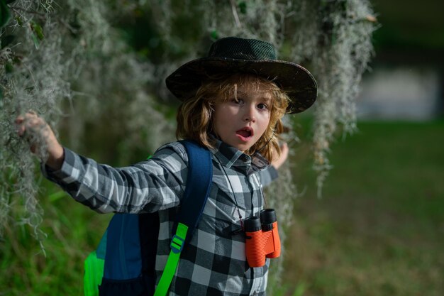 Концепция путешествий и приключений Маленький мальчик-турист-исследователь с биноклем на природе