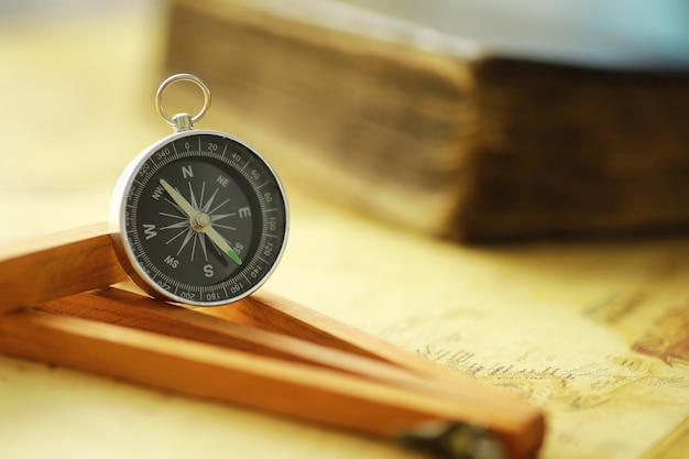 Travel and adventure search concept. vintage aged map with a\
shabby book and compass. shabby book and compass on the table.