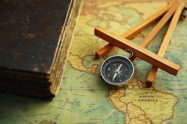 Travel and adventure search concept. Vintage aged map with a shabby book and compass. Shabby book and compass on the table.