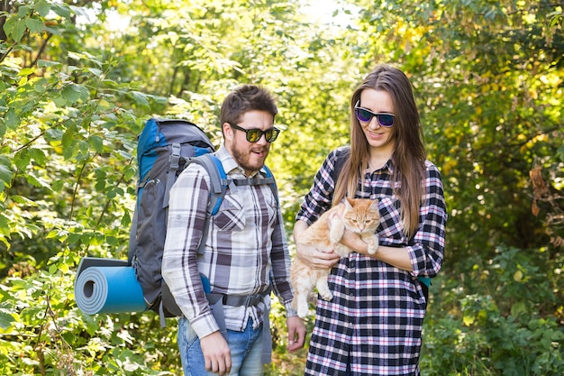 Foto viaggi, avventure, escursioni, turismo e concetto di natura - coppia turistica con gatto che cammina nei boschi.