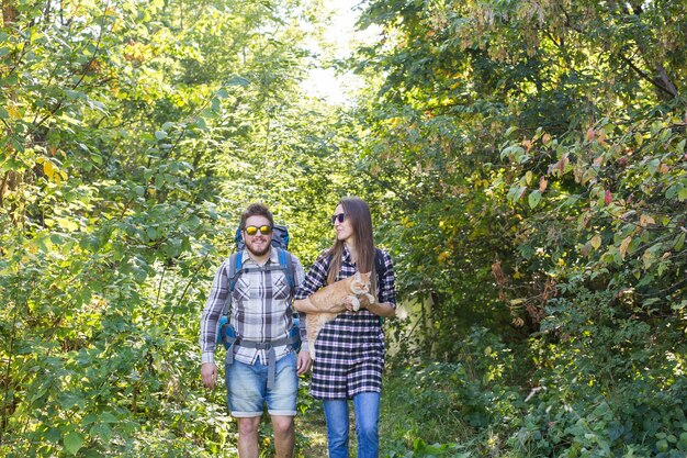 여행, 모험, 하이킹, 관광 및 자연 개념-숲에서 산책하는 고양이와 관광 커플.