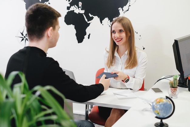 Photo travel agent having client modern office of assistant keeps tickets for the plane