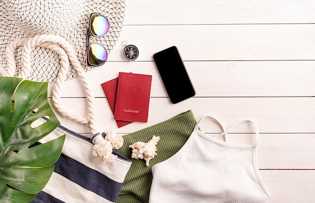 여행 및 휴가 개념. 수영복, 스마트 폰, 여권, 선글라스와 나침반 흰색 나무 배경에 플랫 누워 여행 개체