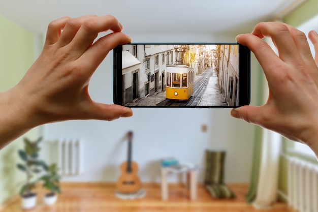家で旅行します。スマートフォン経由でポルトガルのリスボンへのオンライン旅行。画面上の伝説的な黄色の路面電車