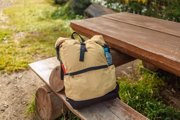 Travel backpack on wooden log bench in autumn forest with birch trees Hiking equipment