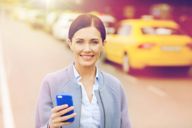 Travel, business trip, people and tourism concept - smiling young woman with smartphone over taxi station or city street
