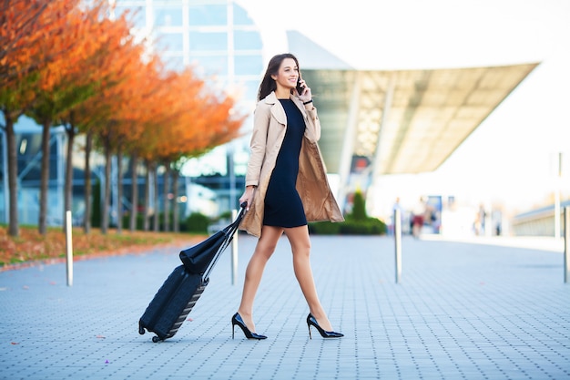 Viaggio. donna di affari in aeroporto che parla sullo smartphone mentre camminando con il bagaglio a mano in aeroporto che va al cancello.