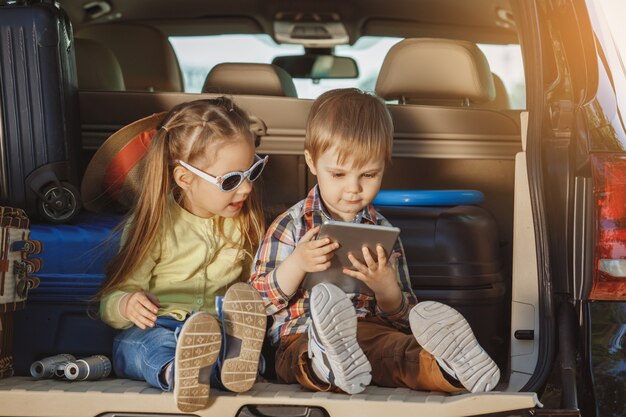 トランクに座っている兄と妹と一緒に車の家族で旅行