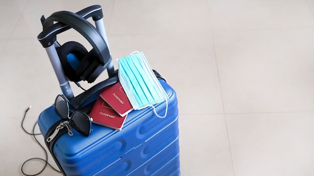 Foto concetto di viaggio maschera passaporto valigia blu per viaggiare durante la pandemia di covid19 vista dall'alto