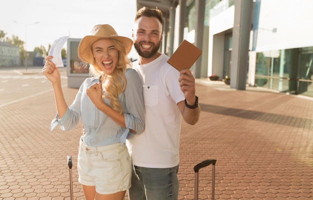 Foto concetto di viaggio coppia che mostra i biglietti vicino all'aeroporto moderno