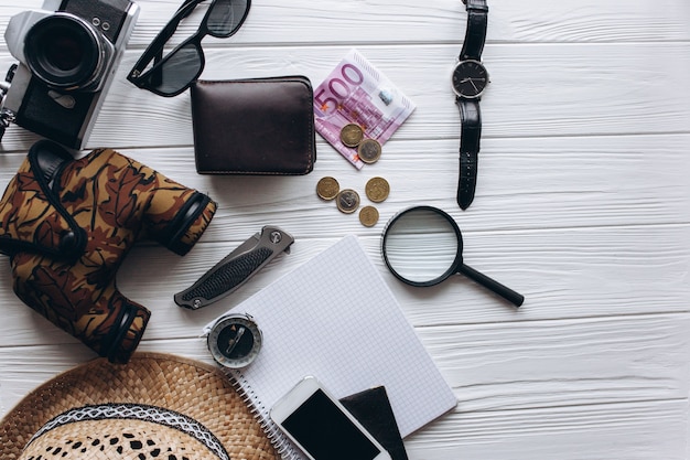 Foto concetto di viaggio, documenti, cappello, bussola, soldi, telefono e fotocamera su uno sfondo bianco