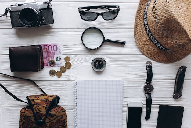 Concetto di viaggio, documenti, cappello, bussola, soldi, telefono e fotocamera su uno sfondo bianco