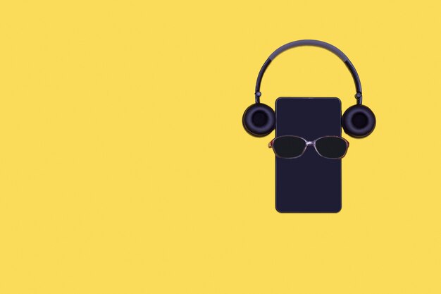 Travel concept  glasses, tablet or phone and headphones on bright yellow surface, flat layout, copy space