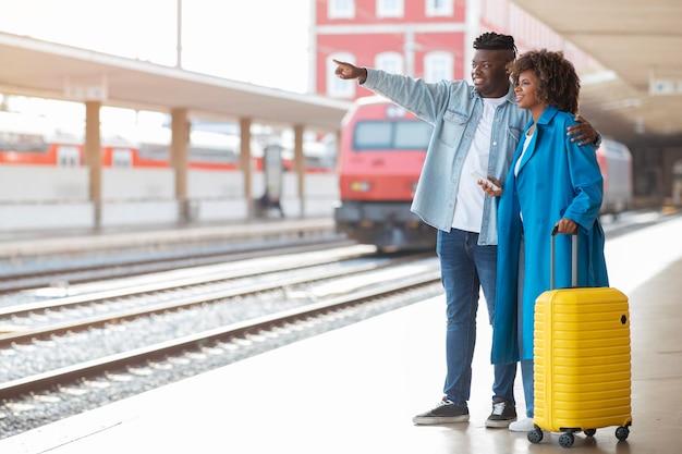 여행 개념 기차역에서 여행 가방을 들고 서 있는 행복한 흑인 커플