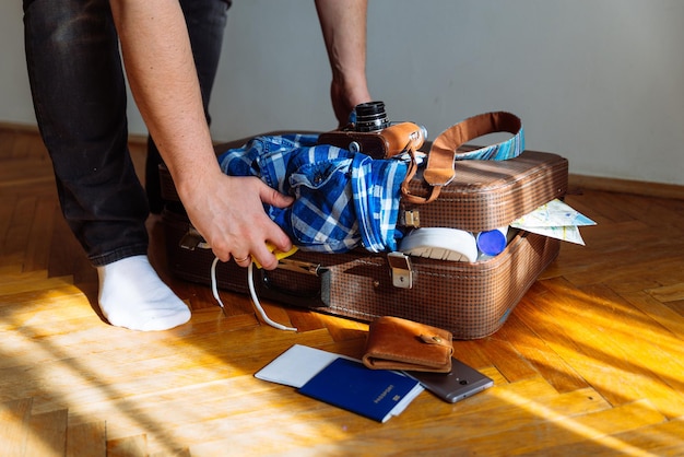 Travel concept man put stuff in suitcase overloaded bag with clothes