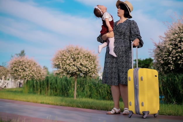 Travel concept mom and daughter with a suitcase are preparing for a trip a child sits on