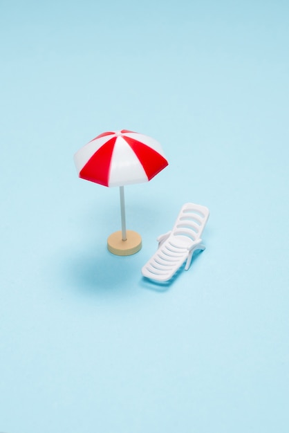 Travel concept. Sun lounger, red umbrella on a blue background. Copy space.