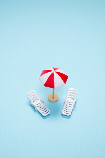 Travel concept. Sun lounger, red umbrella on a blue background. Copy space.