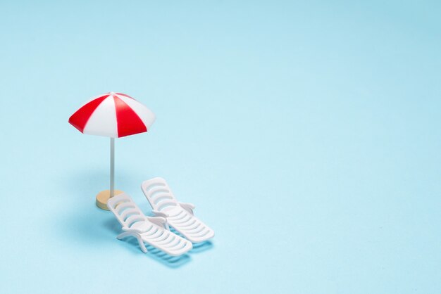 Travel concept. Sun lounger, red umbrella on a blue background. Copy space.