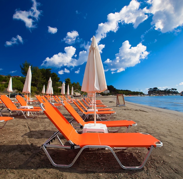 Концепция путешествия - шезлонги с зонтиками на красивом пляже, остров Закинф, Греция