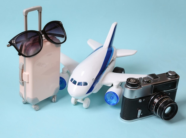 Travel concept toy passenger plane and travel accessories on a\
blue pastel background