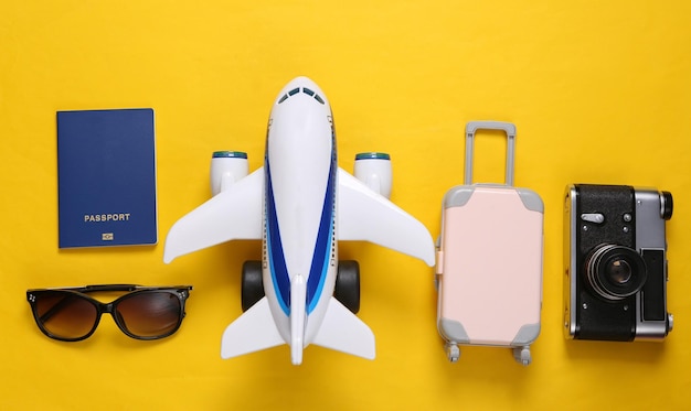 Travel concept toy passenger plane and travel accessories on\
yellow background top view flat lay