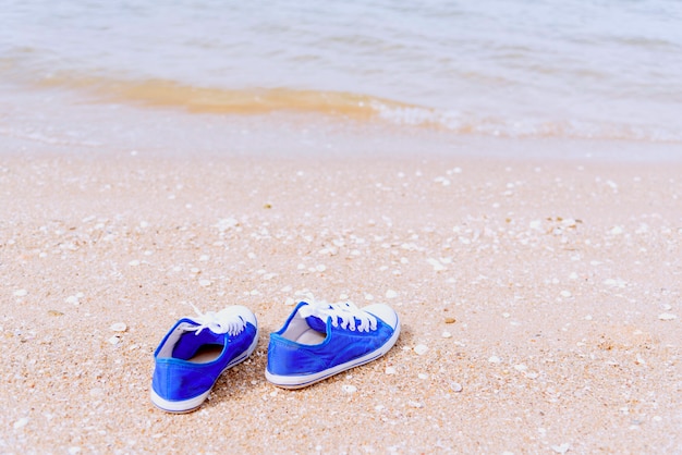 Photo travel concept with blue sneaker on the beach